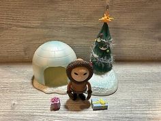 a small toy monkey sitting next to an igloose with presents under it