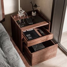 a bed with a wooden night stand on top of it next to a glass vase