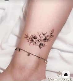 a woman's foot with a flower tattoo on the side of her leg and ankle