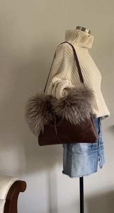 "This large structured shoulder bag measures 16 1/2\"w x 10 1/2\"h and has a shearling detail across the top on the front of the bag. There is one interior cell phone pocket and a wrap closure that loops around a sustainably gathered, naturally shed deer antler. The handle is 29\" long." Shearling Bag, Moroccan Bags, Leather Collar Necklace, Glossier Bag, Leather Handbags Handmade, Structured Shoulder, Black Clutch, Deer Antler, Leather Collar