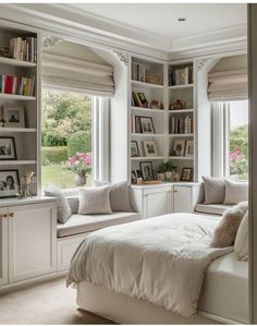 a white bed sitting in a bedroom next to two window sill filled with books