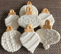 four decorated christmas ornaments on a table cloth with gold trimmings and white frosting