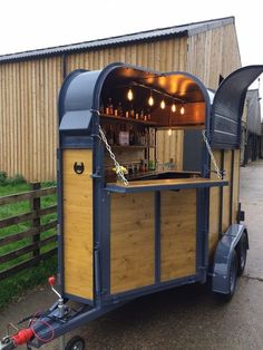 an outdoor bar is attached to the side of a trailer with lights hanging from it