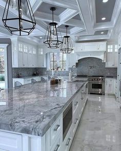 a large kitchen with marble counter tops and white cabinets