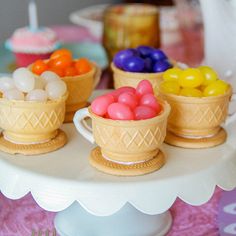 a table topped with cups filled with candy