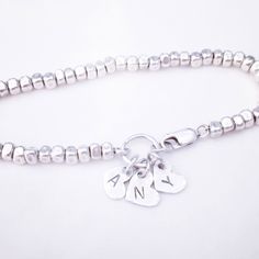 "A sterling silver bracelet with 3 letters engraved on 3 dangling silver hearts. This beautiful bracelet has 3 hearts connected to it by big round link .Three (3) letters of your choosing can be engraved on each one. The bracelet itself is made from Sterling silver nuggets. This lovely bracelet can be worn as a single item or layered with other bracelets to create a more unique and singular look. This bracelet is the perfect gift to any mother or grandmother, a one she'll enjoy wearing everyday. Initials Bracelet, Initial Bracelet Silver, Letter Charm Bracelet, 3 Hearts, Mothers Bracelet, Bracelet Heart, Charms Bracelet, Mom Jewelry, Initial Bracelet