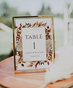 the table number is placed on top of a card board with flowers and leaves around it