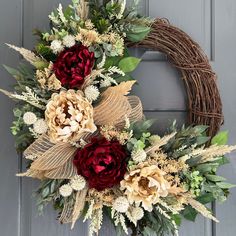 a wreath with flowers and leaves hanging on a door