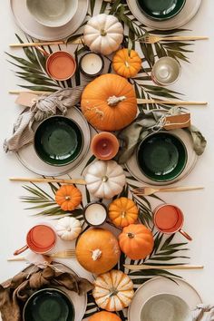 a table topped with plates and bowls filled with different types of pumpkins on sticks