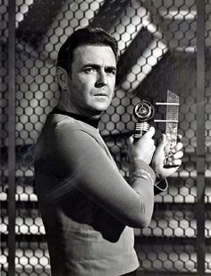 a man holding a toy in front of a chain link fence and looking at the camera