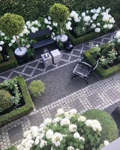 an aerial view of a garden with white flowers and greenery in the center, surrounded by black benches