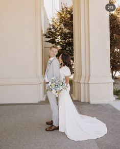 a bride and groom standing in front of an old building with columns on either side