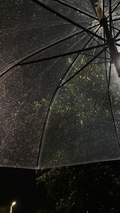 an open umbrella that is sitting on the ground in the rain at night with stars