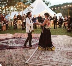 a man and woman standing on top of a rug in front of a group of people