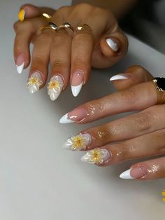 two hands with white and yellow flowers on their nails, one is wearing gold rings