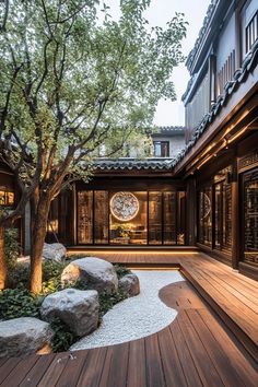 an outdoor area with rocks and trees in the center is lit up by lights that are on either side of the building