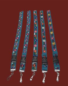 four lanyards with colorful flowers on them are lined up against a red background