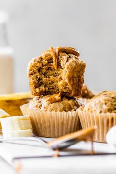 two muffins stacked on top of each other next to some bananas and a glass of milk