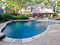 an outdoor swimming pool surrounded by landscaping