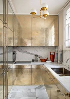 a metallic kitchen with marble counter tops and gold cabinetry is pictured in this image