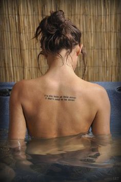 a woman with a tattoo on her back sitting in the water