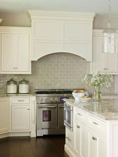 a kitchen with white cabinets and marble counter tops is pictured in this image, there are vases on the stove