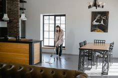 a woman with a mop is cleaning the floor in her living room and kitchen