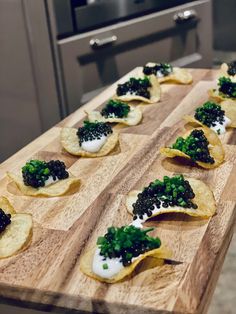 several tortilla shells with black cauliflower and green onions on them sitting on a wooden cutting board