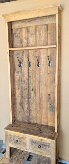 an old wooden bench with two drawers and hooks on the back wall, in front of a tiled floor