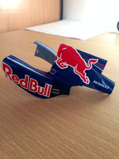 a red bull paper airplane sitting on top of a wooden table