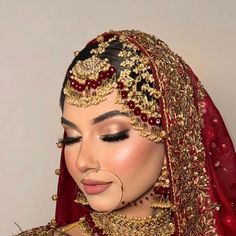 a woman wearing a red and gold bridal veil with her nose ring in the middle