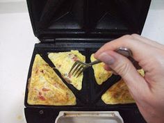 someone is holding a fork over some food in a waffle iron with two pieces of pizza on it