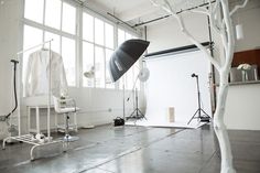 a photo studio with white walls and large windows, including an umbrella in the foreground