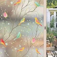 the glass door is decorated with colorful birds on branches and flowers in front of a house