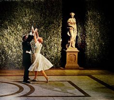 a man and woman dancing in front of a statue