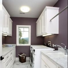 a kitchen with white cabinets and marble counter tops, along with a washer and dryer