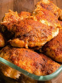 some chicken is in a glass dish on a wooden table and it looks like they have been cooked