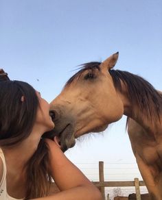 a woman kissing the nose of a horse