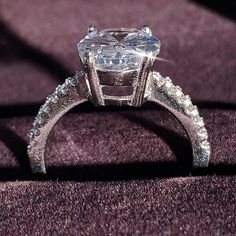 a fancy diamond ring sitting on top of a purple cloth