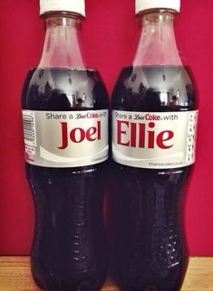 two bottles of soda sitting on top of a wooden table