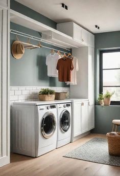 a washer and dryer in a laundry room with clothes hanging on the rack