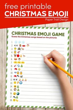 a christmas emoj game with a hand holding a pencil and writing on the paper