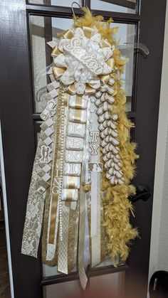 the door is decorated with gold and white ribbons, feathers, and lace on it