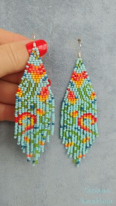 two pairs of beaded earrings are shown on the ground, one has an orange and green flower design