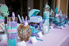 a table topped with candy and candies on top of a purple table cloth covered table