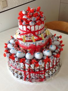 a three tiered cake decorated with chocolates and candies, wrapped in red ribbon