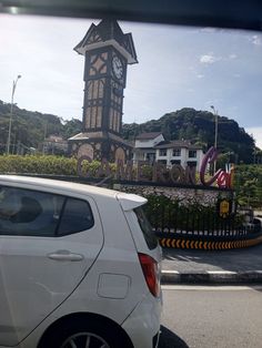 a white car parked in front of a clock tower