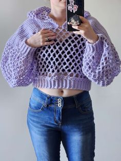 a woman is taking a selfie with her cell phone while wearing a purple sweater