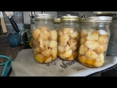 three glass jars filled with food sitting on top of a counter next to a towel