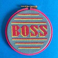 a close up of a embroidery on a blue surface with the word boss in red and yellow